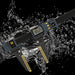 A digital caliper measuring device with a dark gray body, yellow accents, and a display screen, shown diagonally through a dynamic water splash on a black background.