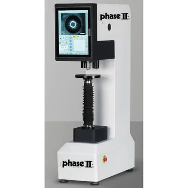 Phase II desktop microhardness tester with a white and black metal frame, featuring an attached touchscreen display and a central compression column, shown against a neutral gray background.